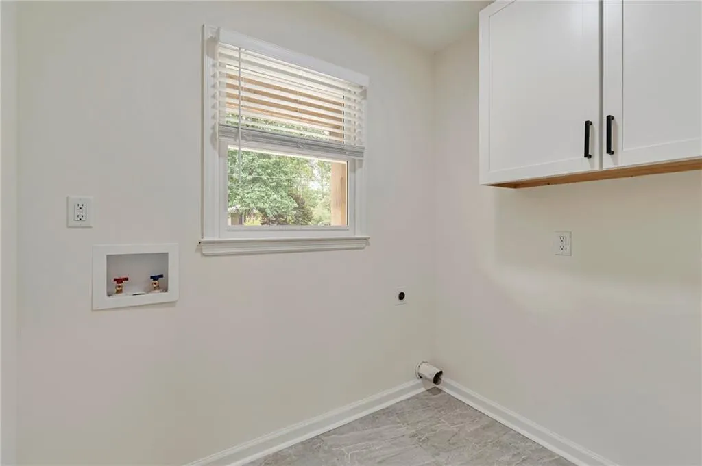 Washroom with hookup for a washing machine, hookup for an electric dryer, and cabinets