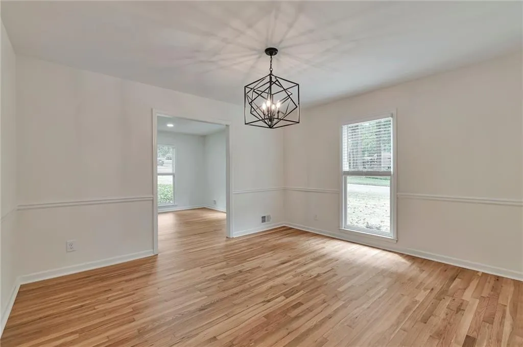 Unfurnished room featuring light wood-type flooring and an inviting chandelier