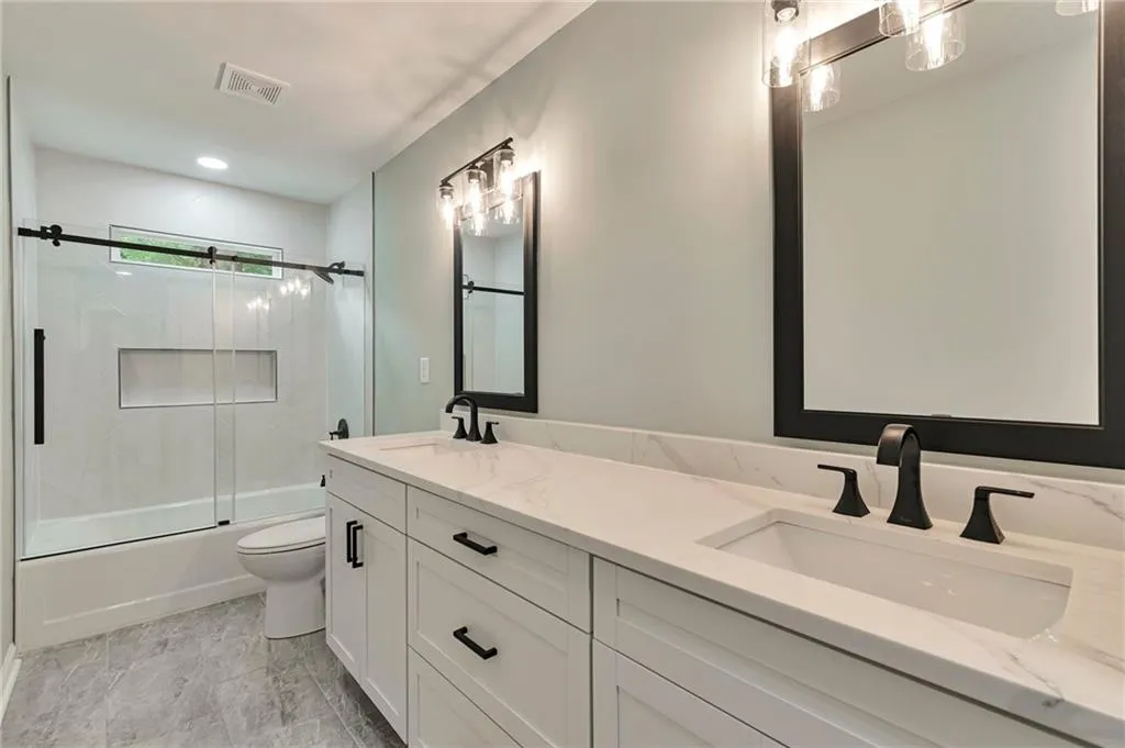 Full bathroom with shower / bath combination with glass door, vanity, and toilet
