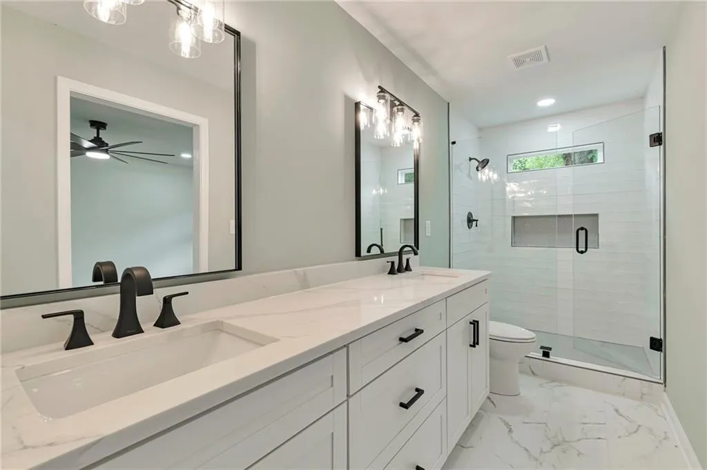 Bathroom with vanity, toilet, a shower with shower door, and ceiling fan