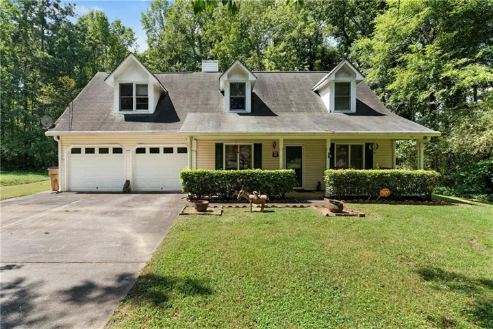 Dormered roofline, two-car garage, covered front porch, and mature landscaping