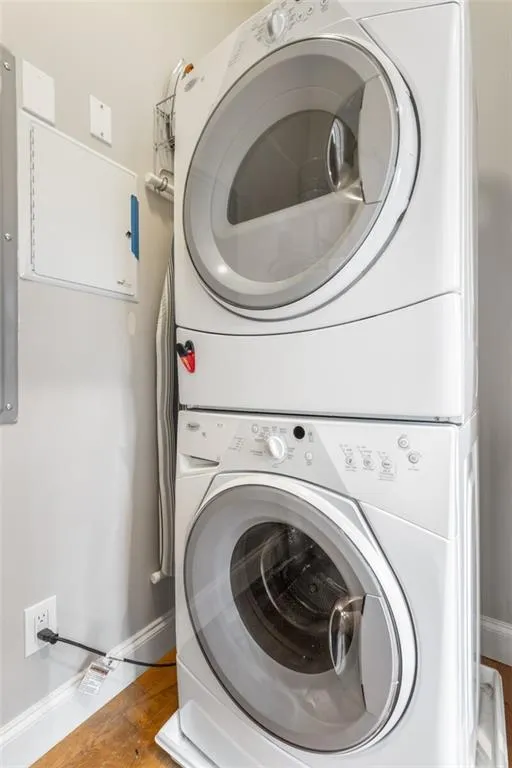 Washroom featuring stacked washing machine and dryer and light wood-style floors