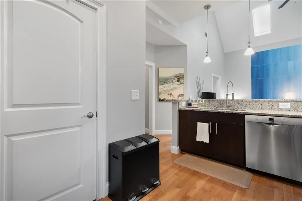 Kitchen featuring dishwasher, light wood-style flooring, dark brown cabinetry, vaulted ceiling, and light stone countertops