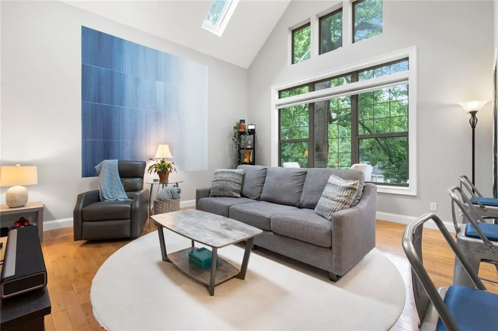 Living room with high vaulted ceiling, a skylight, and light wood finished floors