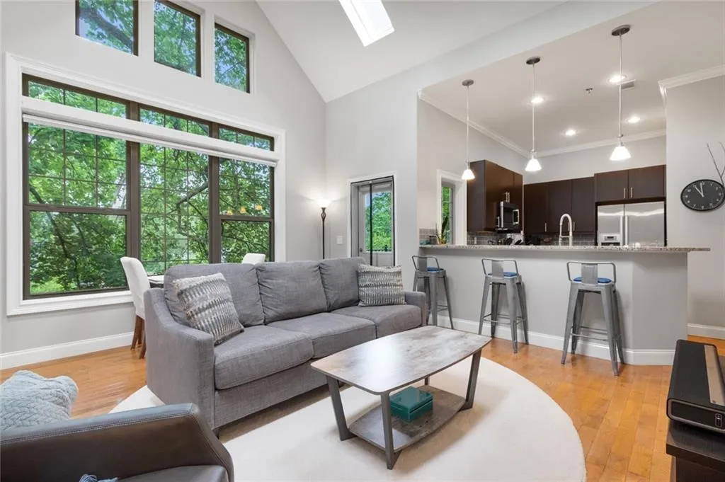 Living area with high vaulted ceiling, light wood-style floors, a skylight, recessed lighting, and crown molding