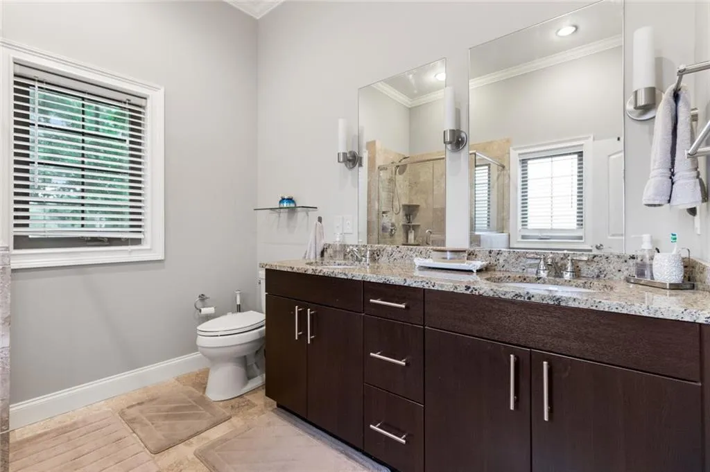 Full bath with double vanity, a shower stall, ornamental molding, and light tile patterned floors
