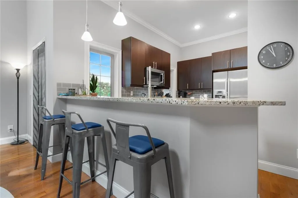 Kitchen with light wood-style floors, decorative backsplash, a kitchen bar, dark brown cabinets, and appliances with stainless steel finishes