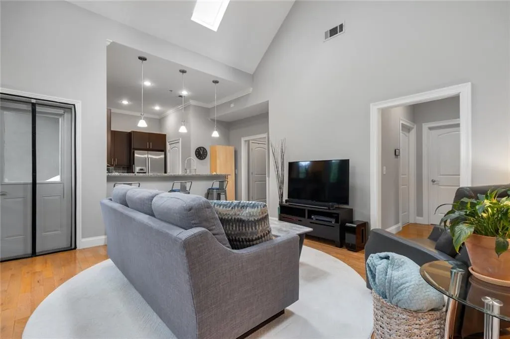 Living area with high vaulted ceiling, a skylight, light wood-type flooring, recessed lighting, and crown molding