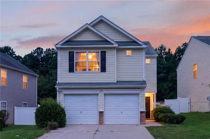 Two-story residence with light-toned siding, a two-car garage, and partial stone facade accents