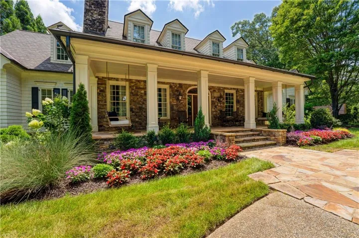 Stone and siding exterior with a covered porch, multiple dormer windows, and a flagstone pathway