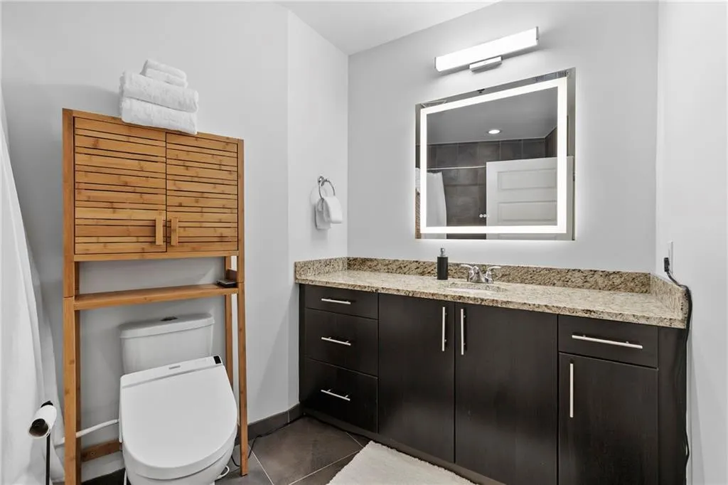 Vanity with stone countertop, dark wood-finish cabinetry, and undermount sink