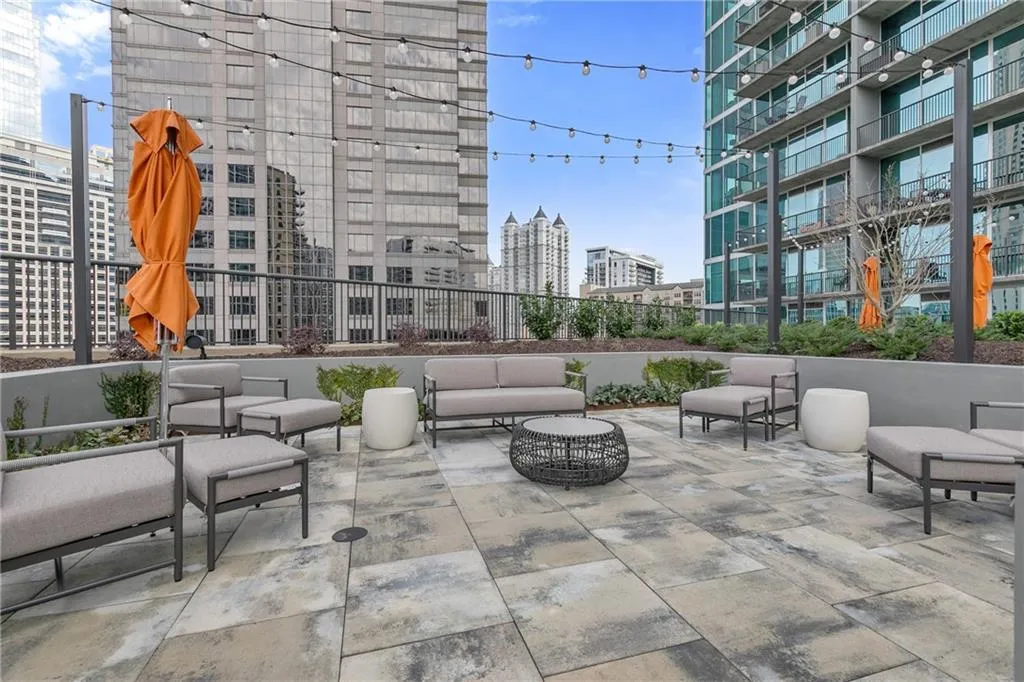 Expansive rooftop patio featuring large format paver flooring, string lighting, and raised planters