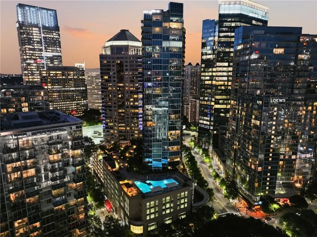 Rooftop pool deck with surrounding cityscape, modern high-rise architecture, and illuminated streetscape