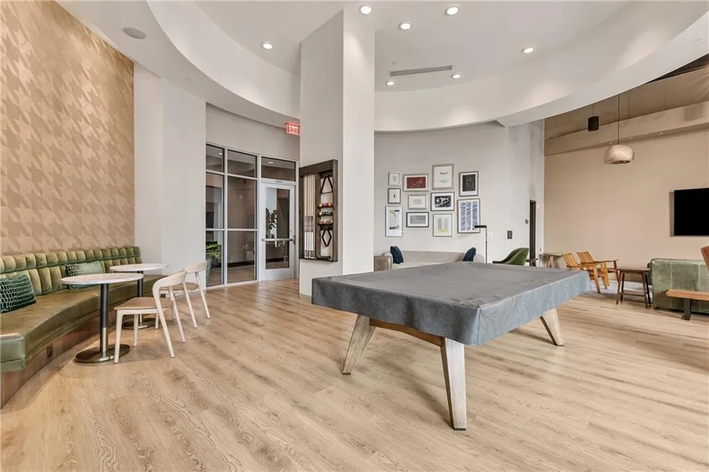 Wood-finish flooring, accent wall with geometric pattern, curved architectural ceiling, recessed lighting, and glass panel entry door
