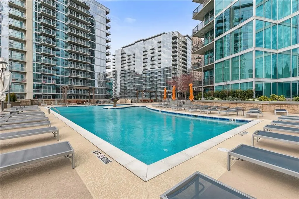 Outdoor swimming pool with integrated fountain feature, surrounded by a concrete pool deck and multiple lounge chairs