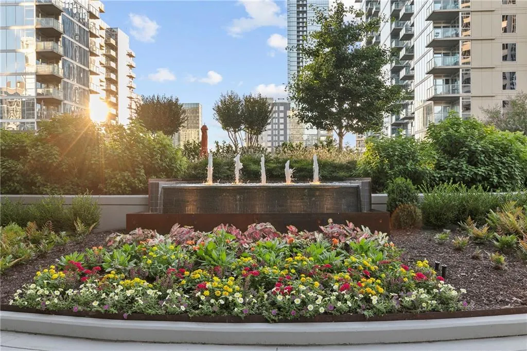 Landscaped courtyard featuring a multi-tiered water feature with multiple fountains, vibrant flowering plants, and mature shrubs