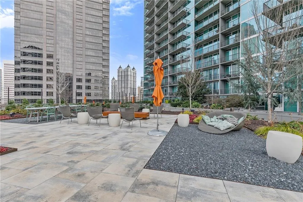 Expansive paver patio with landscaped beds, multiple seating areas, and modern high-rise architecture