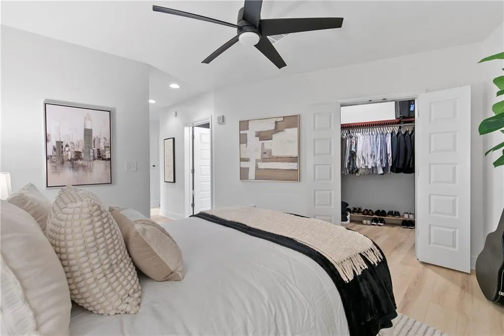 White interior walls, recessed lighting, wood-finish flooring, a black ceiling fan, and bi-fold closet doors