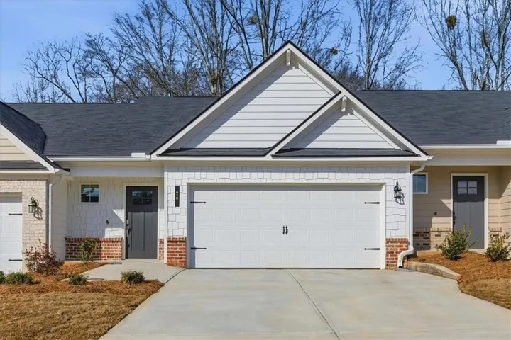 View of front of house featuring covered porch, brick siding, and a garage