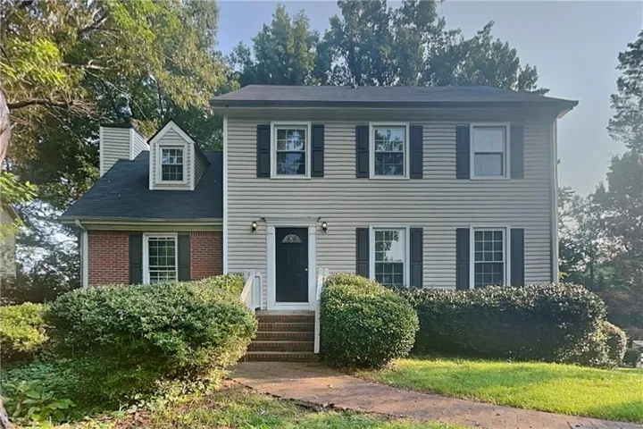 Two-story residence featuring siding and brick accents, a gabled dormer, and dark shutters