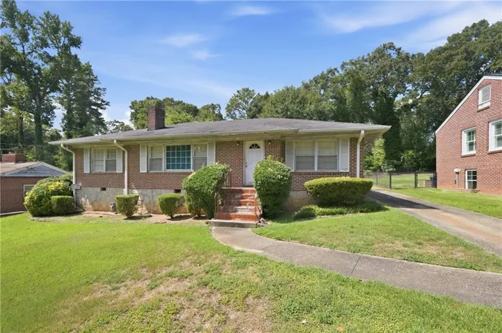 Brick exterior with a prominent front chimney, concrete walkway, and an asphalt driveway