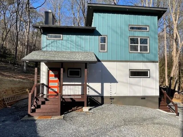 View of front of house featuring crawl space, covered porch, board and batten siding, a shingled roof, and a chimney