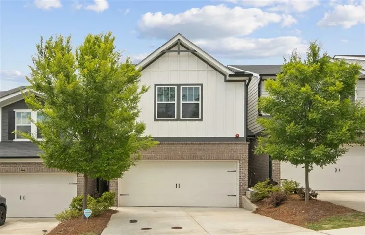Contemporary exterior with white vertical siding, dark trim accents, and brick detailing