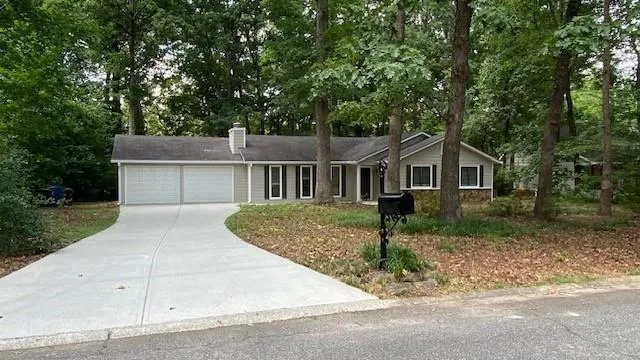Gray siding exterior with white trim, a two-car garage, a paved driveway, a dark shingle roof, and a black mailbox