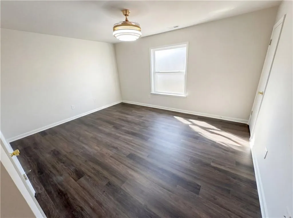 Empty room featuring dark wood-type flooring and baseboards