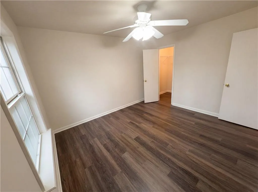 Unfurnished bedroom with dark wood finished floors, a spacious closet, and ceiling fan