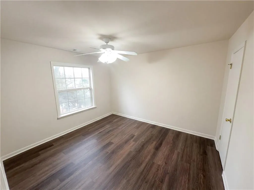Unfurnished room featuring dark wood-style floors and ceiling fan
