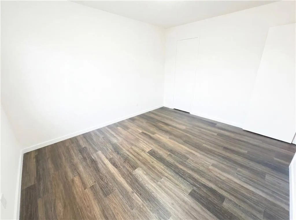 Unfurnished room with dark wood-style floors and baseboards