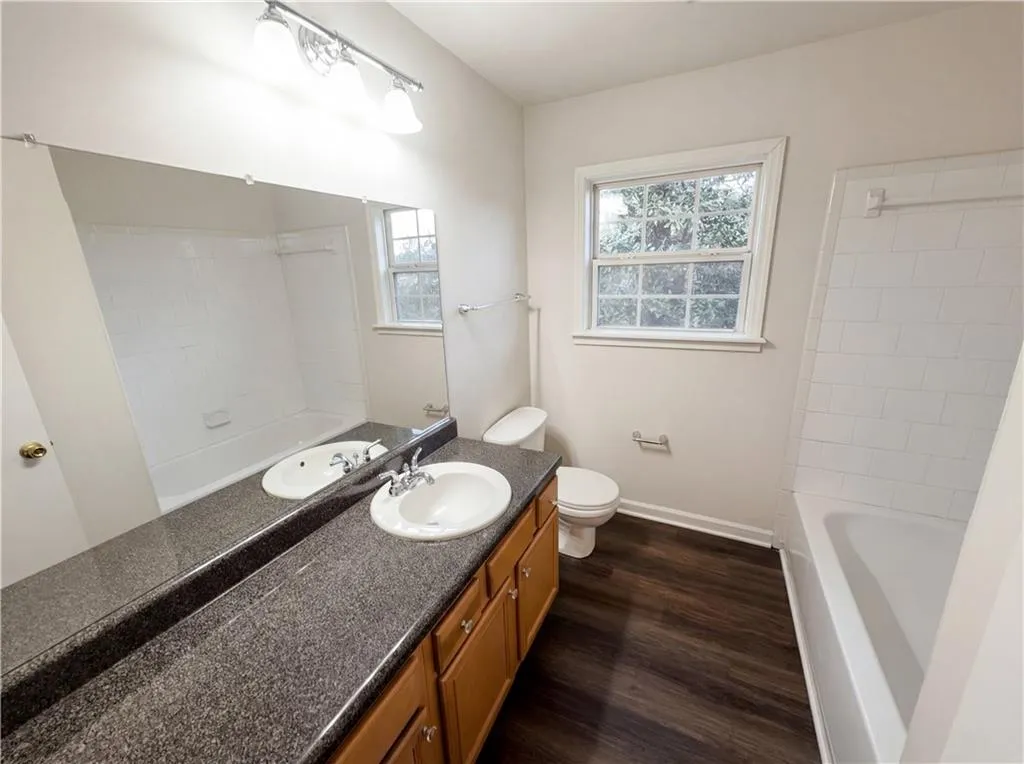 Full bathroom with vanity, plenty of natural light, bathtub / shower combination, and dark wood-style floors
