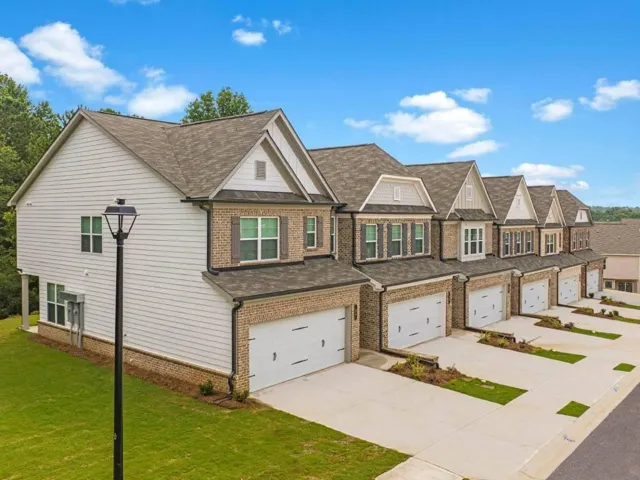 Residential exterior featuring brick and horizontal siding, gabled rooflines, attached garages, and individual driveways