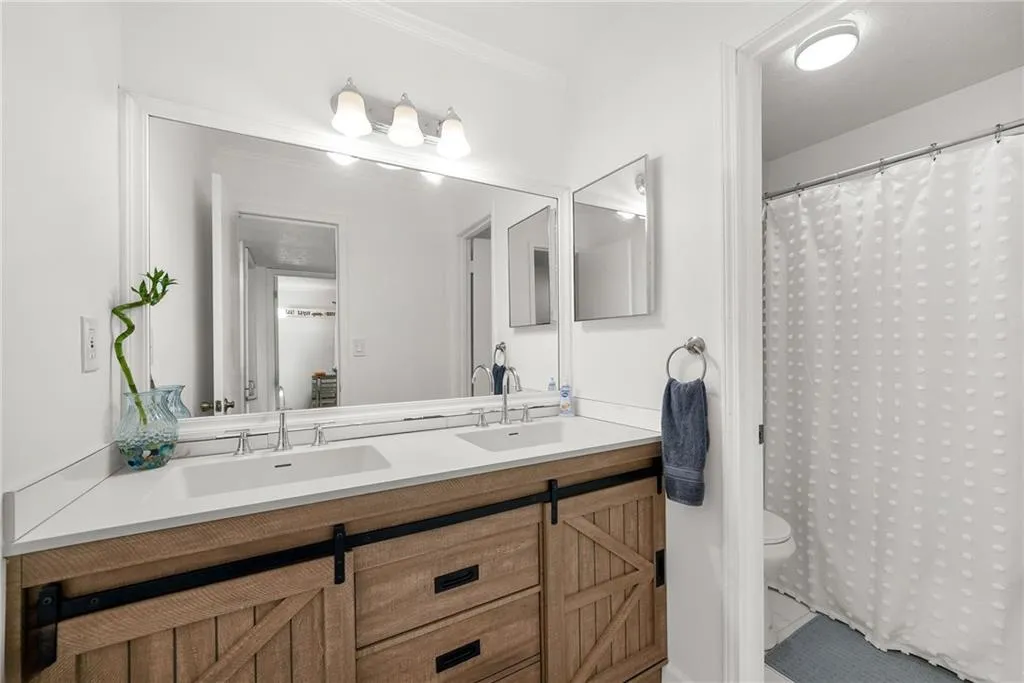 Full bath with double vanity, curtained shower, and ornamental molding