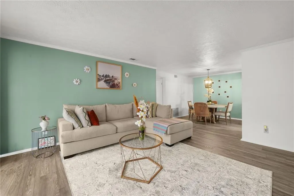 Living area with wood finished floors, crown molding, and a textured ceiling