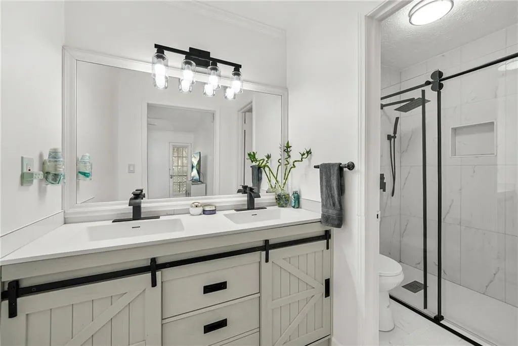 Bathroom featuring double vanity and a marble finish shower