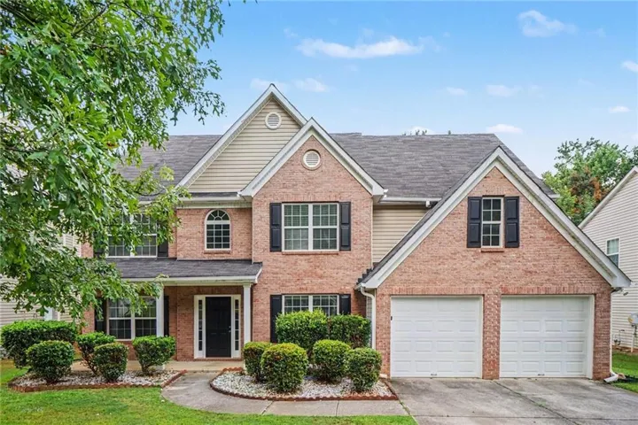 Brick exterior with gabled roof lines, dual garage doors, and a covered entry