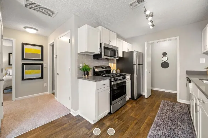 Kitchen with white cabinetry, stainless steel appliances, grey subway tile backsplash, and wood-finish flooring