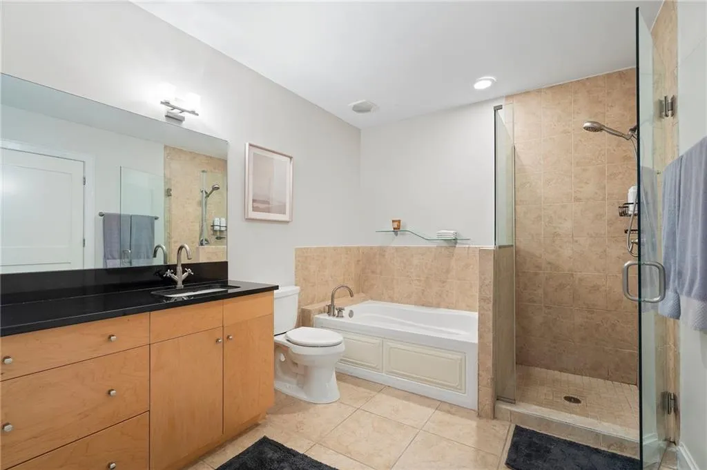 Full bathroom featuring tile patterned floors, a stall shower, vanity, and a garden tub
