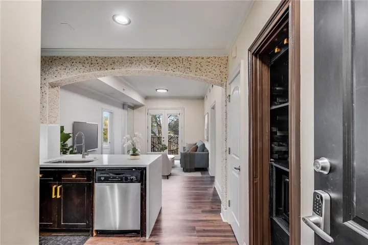 Kitchen island with an undermount sink, a stainless steel dishwasher, and dark wood cabinetry