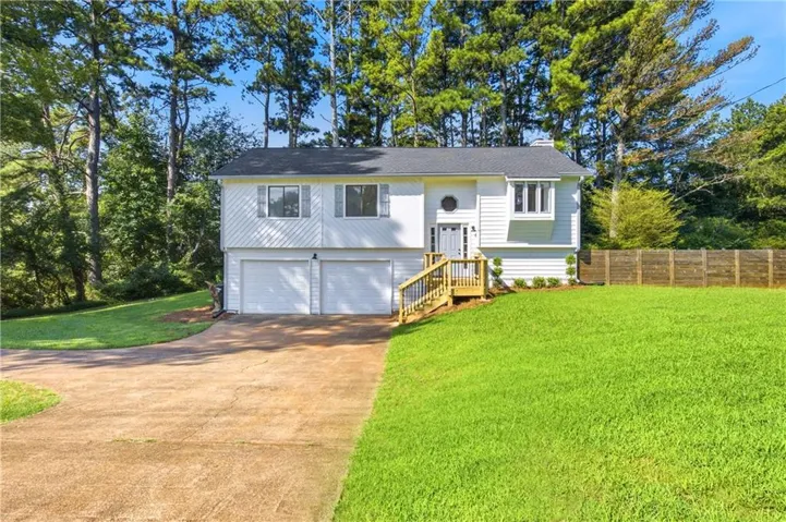 Split-level home featuring white siding and a dark roof