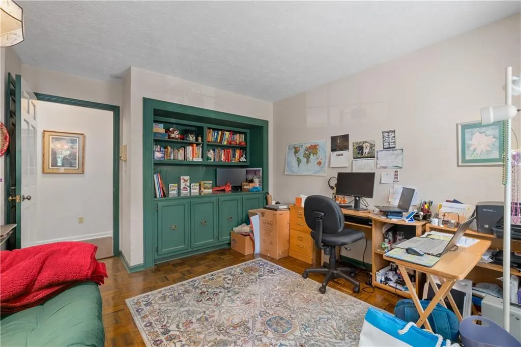 Office area with built in features, dark parquet flooring, and a textured ceiling