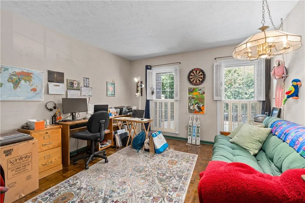 Office area featuring dark parquet flooring, an inviting chandelier, and a textured ceiling