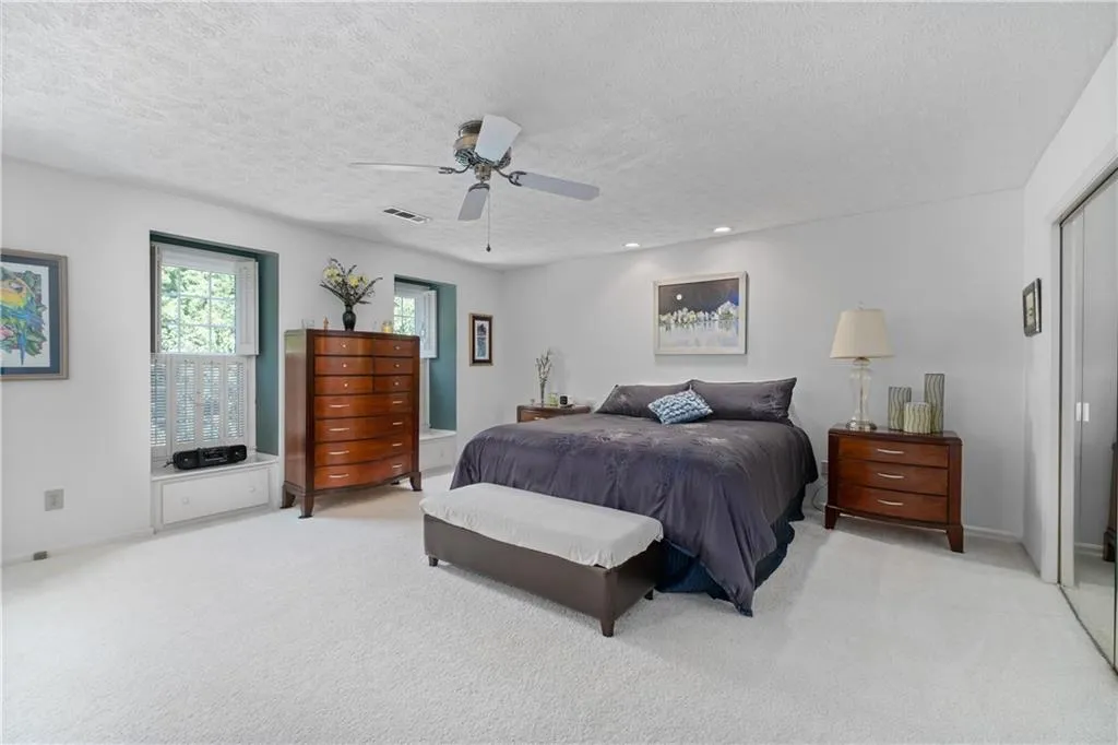 Carpeted bedroom featuring ceiling fan, a closet, and a textured ceiling