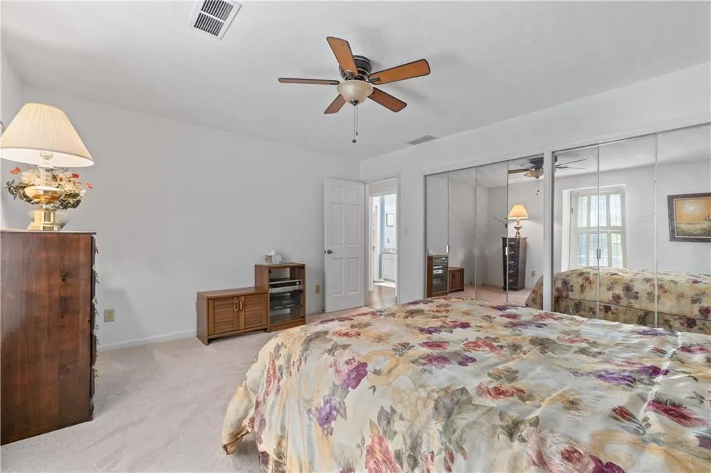Carpeted bedroom with two closets and ceiling fan