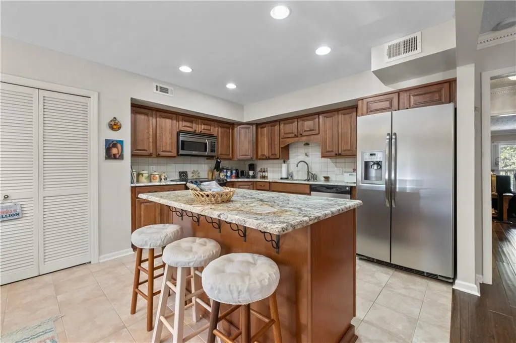 Kitchen with stainless steel appliances, a kitchen breakfast bar, backsplash, and a kitchen island