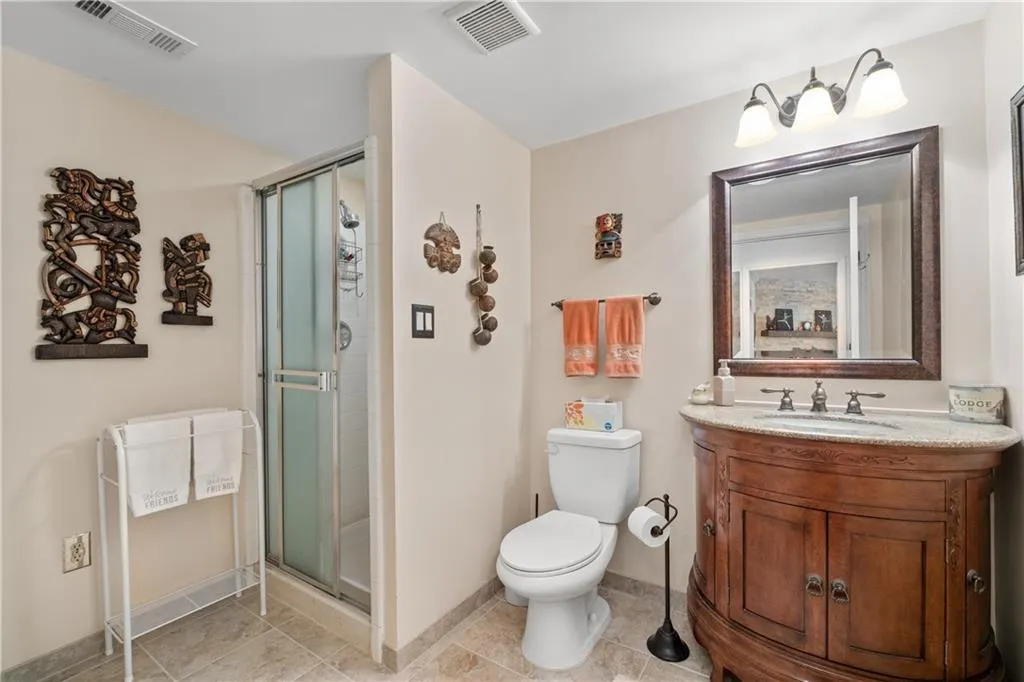 Bathroom featuring a shower with shower door, tile floors, toilet, and vanity with extensive cabinet space