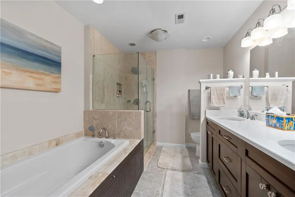 Full bathroom featuring double sink vanity, tile flooring, shower with separate bathtub, and toilet