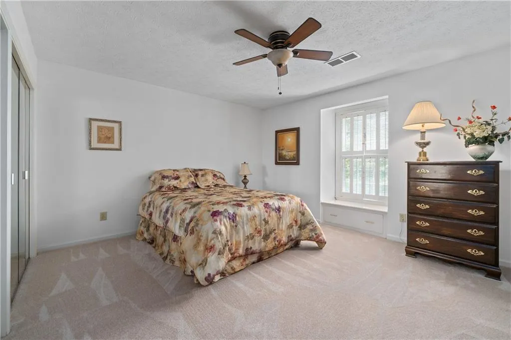 Carpeted bedroom with a closet, ceiling fan, and a textured ceiling